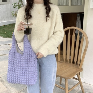 Detailed close-up of a purple popcorn texture tote bag worn by a model in nature