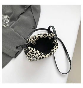 Flat lay of leopard print drawstring bucket bag with black strap and suit jacket