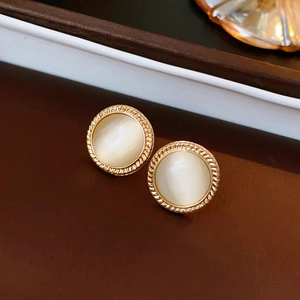 Macro shot of vintage round cat eye stone earrings with a textured gold metal frame