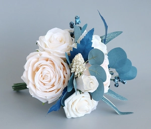 Close-up of elegant wedding bouquet with cream roses and blue foliage on gray background