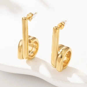 Detailed close-up of gold-plated C-shaped stainless steel earrings with polished finish