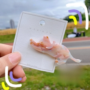 Detail of pink marble acetate cat hair clip on brand card with nature background