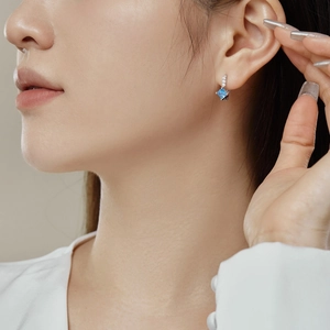 Macro detail of S925 silver hoop earring featuring a square light blue gemstone and zircon