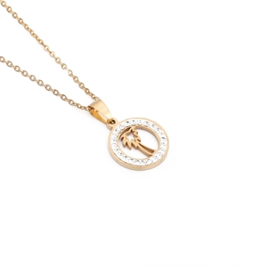 Macro shot of gold-plated shell pendant with engraved palm tree and zircon details