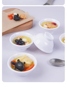 Macro detail of miniature herbal chicken soup model with goji berries and tiny metal spoon