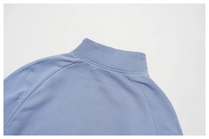 Detailansicht eines hellblauen Sweatshirts mit geripptem Kragen und Raglanärmel-Nähten