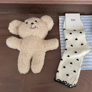 Close-up of crew socks with heart patterns, ruffled edges and a cute teddy bear