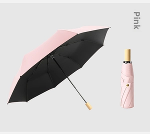 Pink folding umbrella detail with black sunshade coating and natural wood handle
