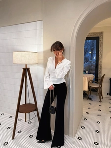 Détail de la blouse blanche à col en V avec taille cintrée et rubans élégants aux poignets
