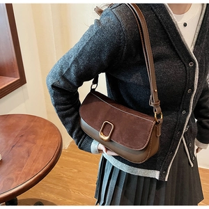 Detail of vintage brown shoulder bag with suede flap and bronze D-ring buckle accessory