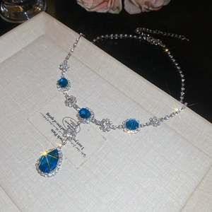 Vue détaillée du collier argenté avec grands cristaux bleus en goutte et des strass