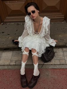 Detail of white ruffle chiffon dress with V-neckline and tie detail in retro style