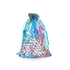 Detailed view of blue organza drawstring bag with coral pattern filled with white pearls