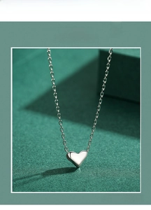 Close-up of polished sterling silver heart pendant on a delicate cable chain necklace