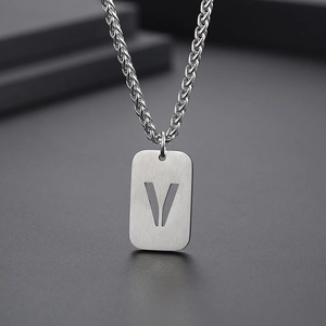 Vue macro d'un pendentif rectangulaire argenté avec lettre V sur chaîne tressée