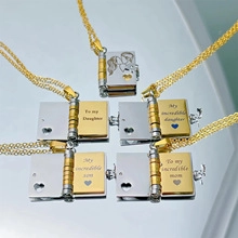 Detailed view of book-shaped locket pendants with engraved sentimental messages in gold and silver