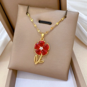 Detailed macro view of a gold flower necklace with red heart-shaped petals in a beige box