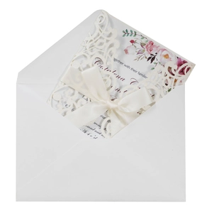 Detail of laser-cut glitter wedding invitation with satin bow and floral insert