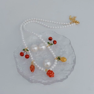 Detail shot of a pearl necklace with cute fruit pendants like strawberry and cherry.