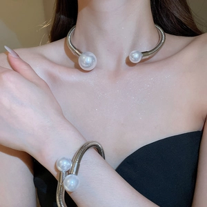Detail of silver twisted rope choker and bracelet set featuring large white pearls on a model
