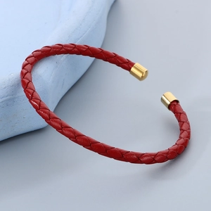 Dettaglio del bracciale in pelle intrecciata rossa con eleganti finali in metallo dorato