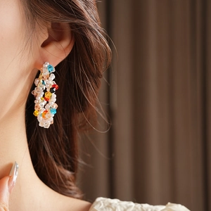 Primo piano di orecchini a cerchio con filo intrecciato, perle e vivaci perline colorate