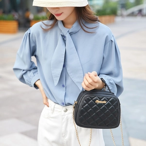 Classic black quilted handbag with gold chain strap shown on a model in urban setting