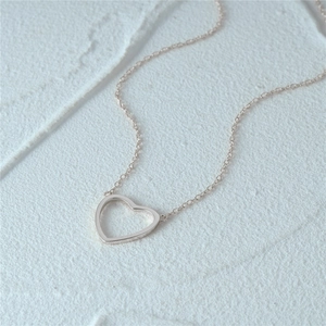 Close-up of minimalist S925 sterling silver hollow heart pendant on a fine chain