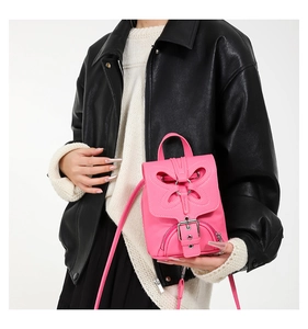 Détail d'un sac à main rose vif en cuir grainé avec une découpe décorative en papillon