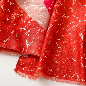 Detailed macro view of soft red winter scarf with golden foil texture and fine fringes