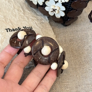 Close-up of bohemian handmade coconut shell and wood bead bracelet held by hand