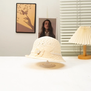Detail view of cream straw cloche hat featuring decorative flowers and pearl accents