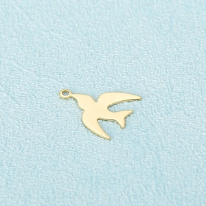 Polished gold swallow bird pendant in stainless steel on light blue textured background