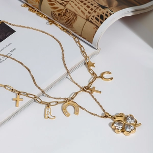 Detailed close-up of gold clover heart charms and horse shoe pendant on chain