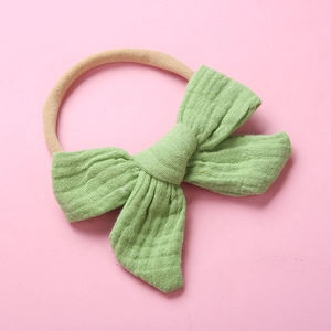 Detail of light green muslin bow headband with soft crinkle texture for babies
