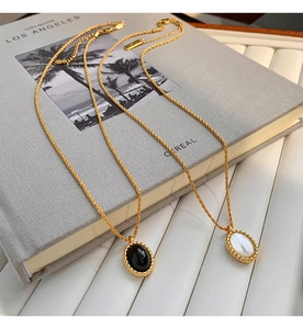 Detail of vintage oval black onyx and white shell pendants on gold necklaces over a book