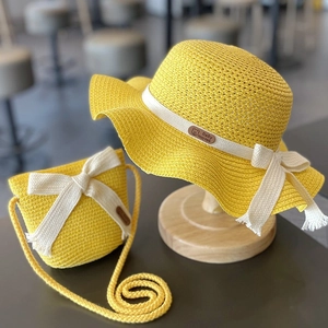 Bright yellow kids straw sun hat and matching crossbody bag set with white bows