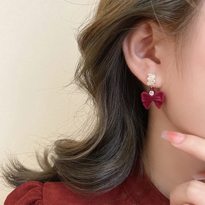 Gros plan de boucles d'oreilles nœud en velours rouge avec clous dorés sertis de diamants