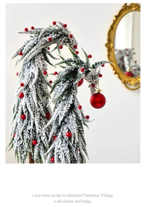 Macro detail of flocked green Christmas tree with red berries and a festive red bauble