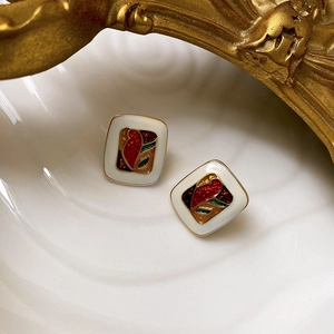 Close-up of vintage square oil painting earrings with red floral patterns on shell tray