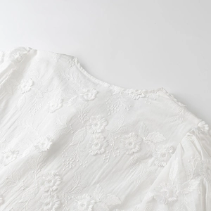 Detailed close-up of white blouse neckline with delicate 3D floral embroidery patterns