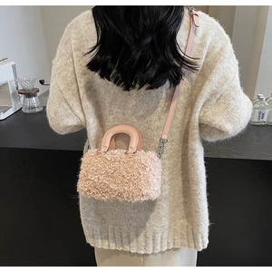 Pink faux fur box bag styled as a crossbody on a model wearing a beige sweater