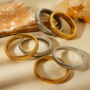 Detailed macro view of seven gold and silver spring-style titanium steel bracelets on stones