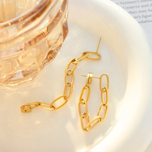 Minimalist golden double chain drop earrings displayed on a white ceramic plate