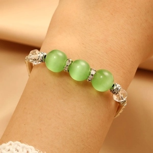 Detail of silver bracelet with green cat-eye beads and engraved metallic spacers