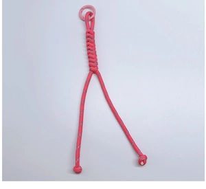 Detail of pink hand-woven paracord keychain with reflective thread and spring buckle