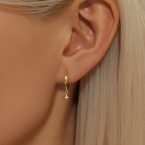 Close-up of gold star dangle hoop earrings with sparkling zircon on a female model