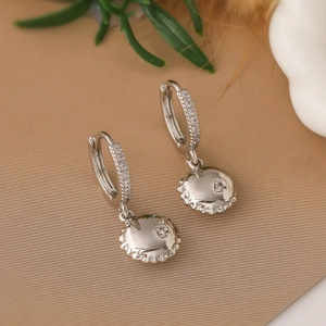 Dettaglio di orecchini a palloncino geometrici placcati in argento con zirconi lucidi