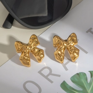 Schicke goldene Schmetterlings-Ohrstecker im geometrischen Metalldesign auf schlichtem Hintergrund