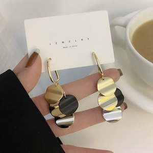 Detail of vintage round disc tassel earrings featuring gold, black and silver metal finish